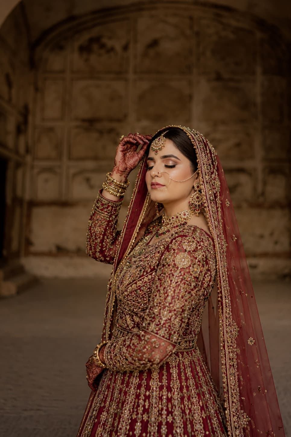 A bride photographed against warm, textured heritage architecture.