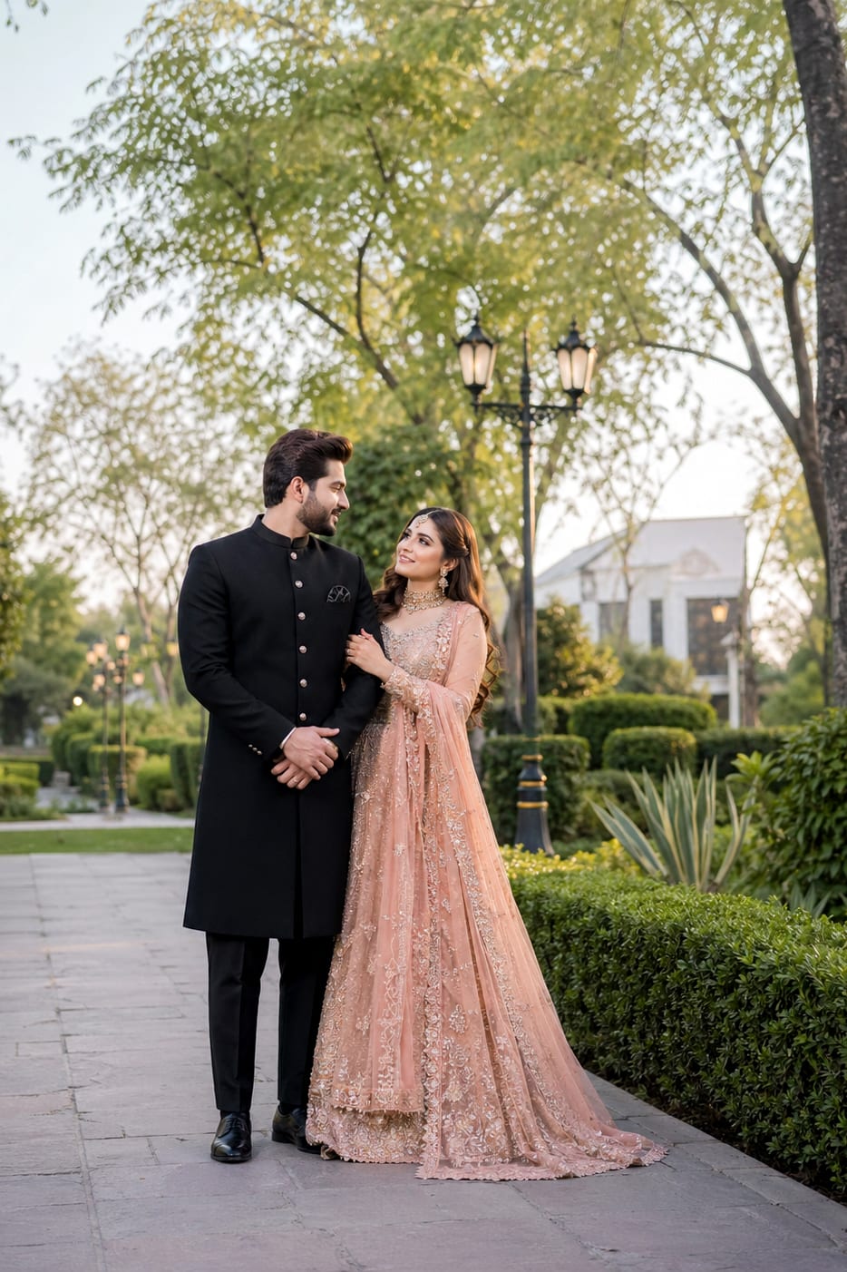 A formally dressed couple standing together in a garden setting