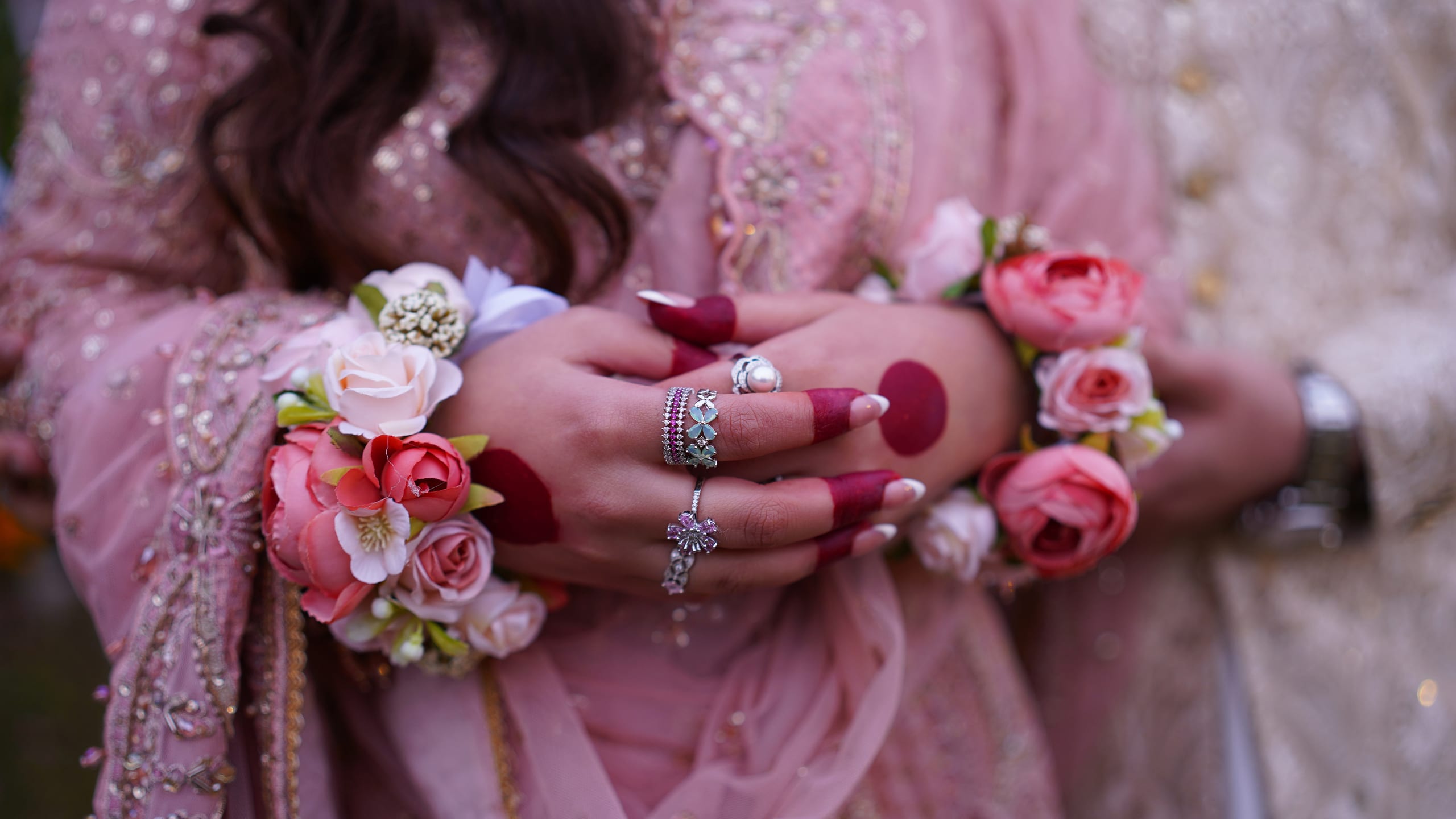 Close-up of hennaed hands with floral jewelry and rings